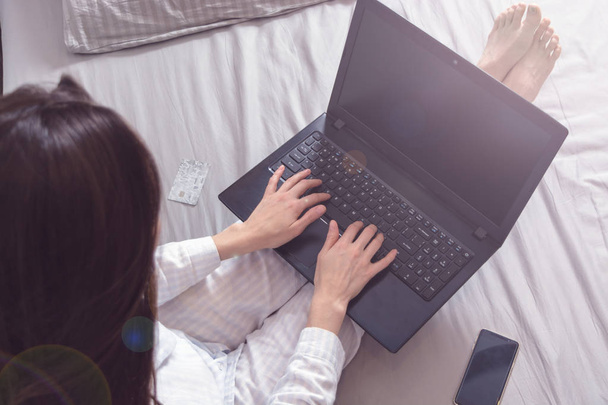 Женщина-фрилансер в пижаме лежит в постели и работает над ноутбуком, блогером, писателем. обрезанный вид сверху
 - Фото, изображение