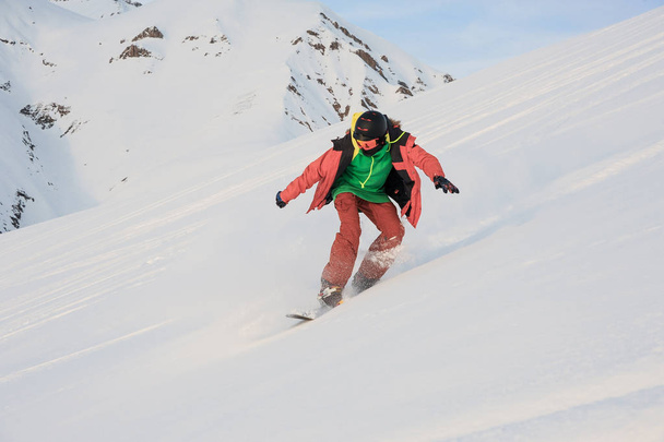 Active snowboarder sliding down the snowy slope - Foto, afbeelding