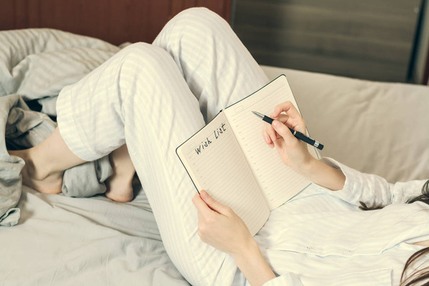 Περικομμένη εικόνα μιας γυναίκας στο πιτζάμες ξαπλωμένη στο κρεβάτι και να είναι ένα κομμάτι της επιθυμίας - Φωτογραφία, εικόνα