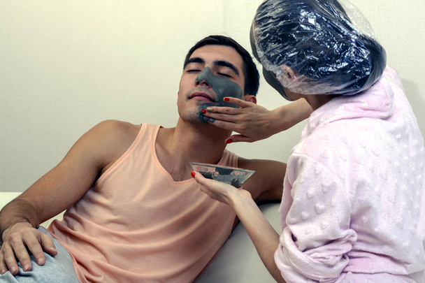 A young married couple takes care of the skin with clay masks at home. Spa day. Wellness - Photo, Image