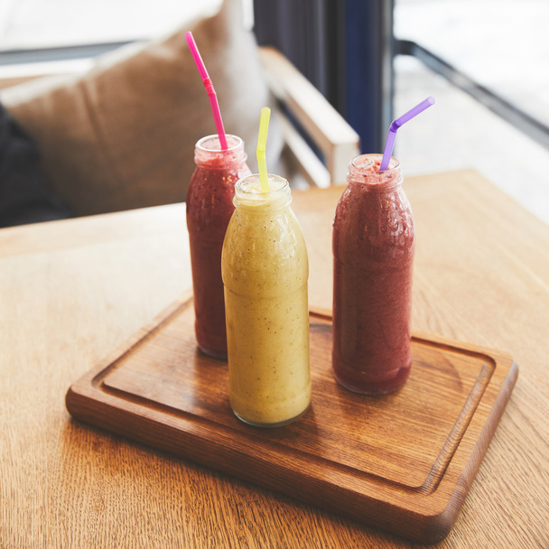 Bouteilles avec smoothies de fruits frais et de baies sur la table
 - Photo, image