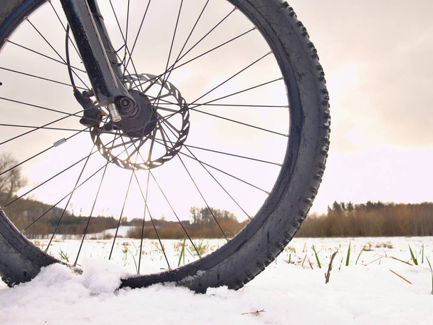 Detalle de la bicicleta delantera en un sendero de invierno, camino cubierto de nieve. Fondos deportivos
 - Foto, imagen