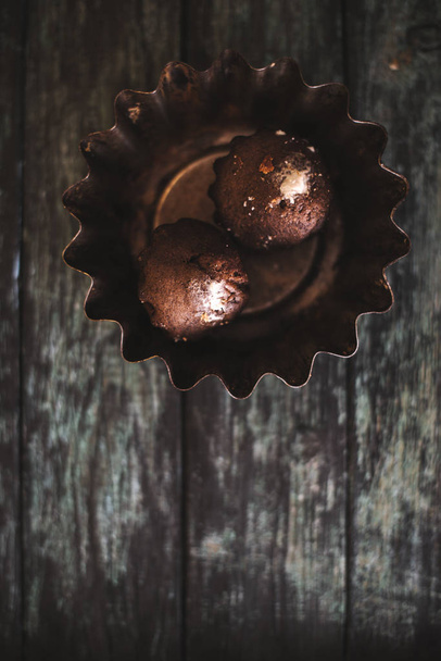 Cupcakes on a dark wooden background in an iron dish. - Zdjęcie, obraz
