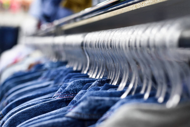 Denim overhemden hangen aan kledinghangers in een rij. Kleding Shop. Style Concept - Foto, afbeelding