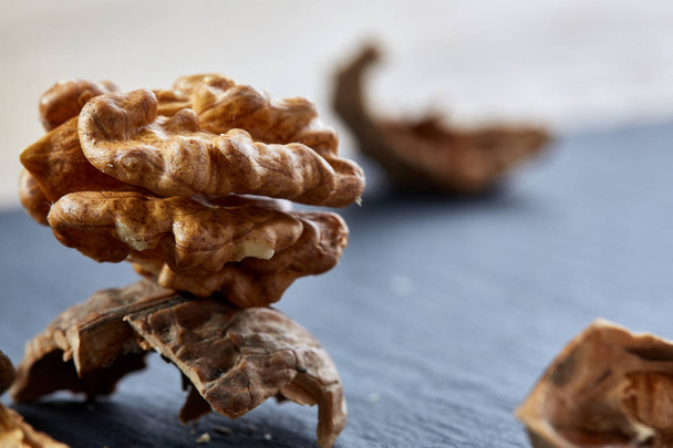 Top view close-up shot of cracked walnuts on dark background, shallow depth of field, macro - Foto, Imagem