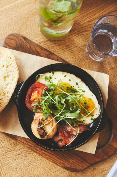 Gebakken eieren met tomaten en champignons in de pan op tafel - Foto, afbeelding