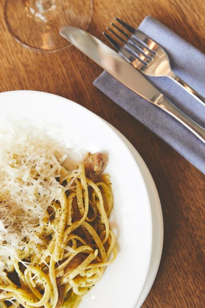 Italiaanse pasta met champignons en pesto, geserveerd op een witte plaat - Foto, afbeelding