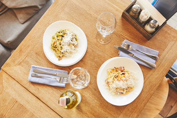 Diner met Italiaanse pasta in platen geserveerd met wijn - Foto, afbeelding