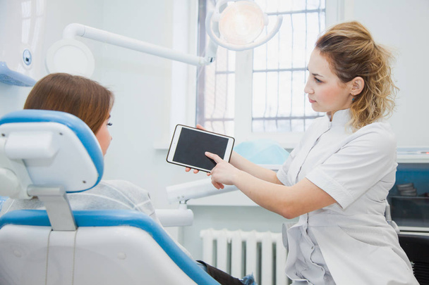 Female dentist and patient discussing treatments in a tablet application. - Valokuva, kuva
