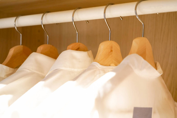 row of men and women shirts on the hanger, hanging in the wardrobe - Valokuva, kuva