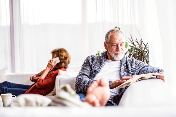 Senior couple with smartphone relaxing at home. - Фото, изображение