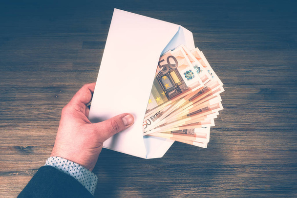 Man holding pile of 50 euro banknotes in white envelope. Finances and budget concept - Foto, Imagem