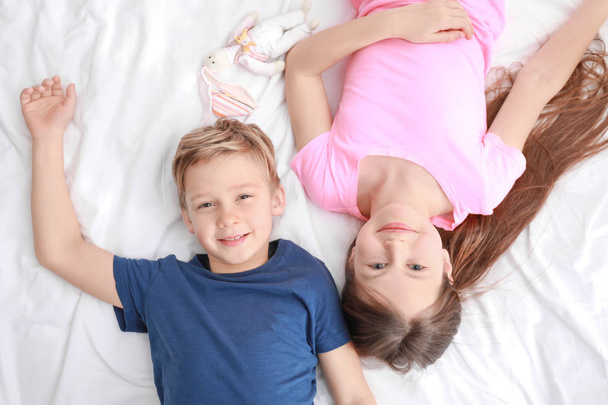 Cute little brother and sister lying on bed at home - Valokuva, kuva