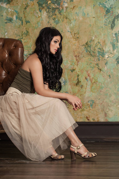 Atraktivní žena bruneta sedí na pohovce na zelené stěny  - Fotografie, Obrázek