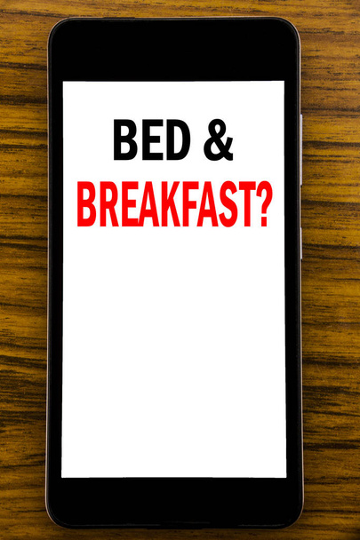 Handschrift aankondiging tekst tonen Bed Breakfast. Businessconcept voor vakantie reis reizen geschreven op mobiele telefoon mobiele telefoon met houten achtergrond met ruimte op tafel - Foto, afbeelding