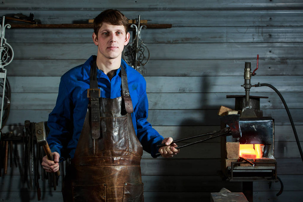 Young muscular man working on a blacksmith with metal - Photo, image