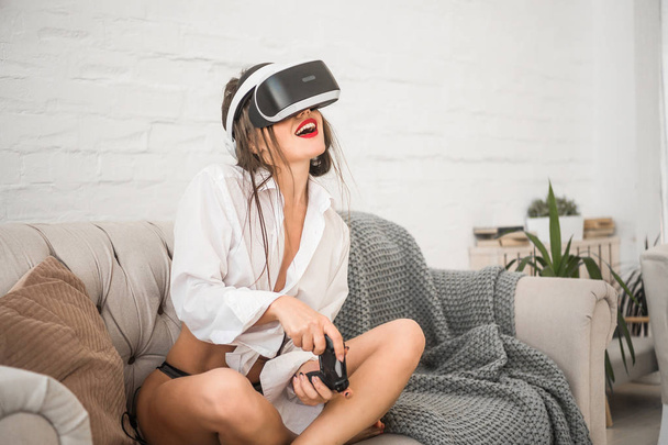 Jovem feliz está jogando vídeo game em 3D simulador de realidade virtual usando fone de ouvido
. - Foto, Imagem