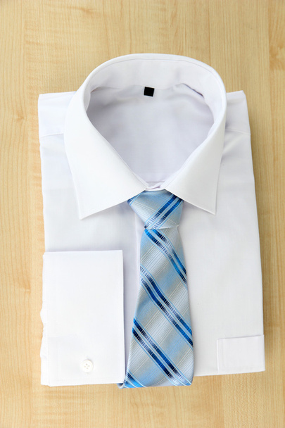 New white man's shirt with color tie on wooden background - 写真・画像