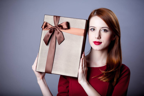 Jeune fille rousse avec boîte cadeau sur fond gris
  - Photo, image