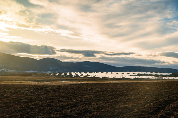 Zonsondergang over zonne-energiecentrale in platteland. - Foto, afbeelding