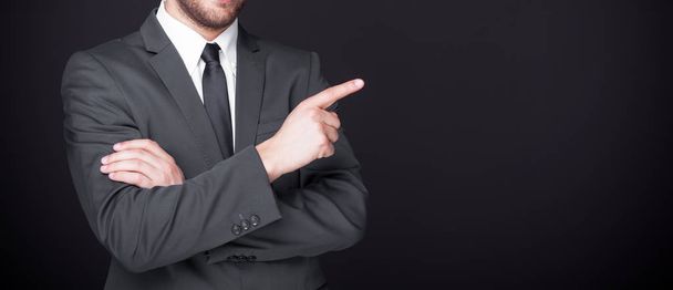 Businessman pointing finger at copy space on black background - Photo, image