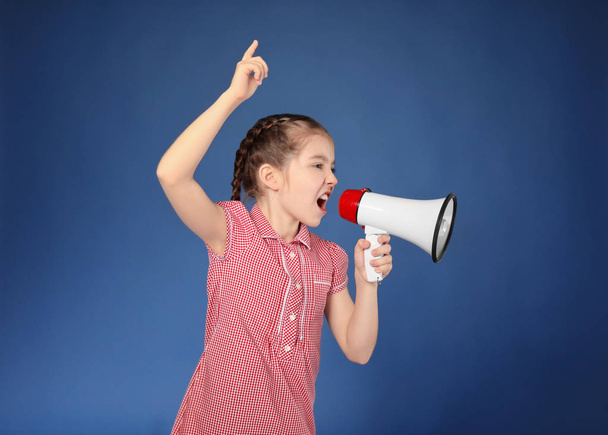 Emotional little girl shouting into megaphone on color background - Photo, Image
