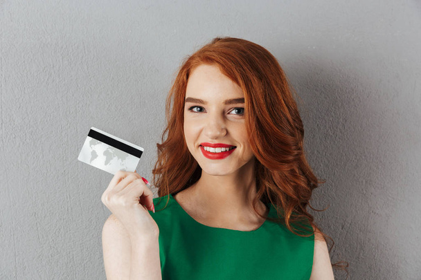Happy redhead young woman holding credit card. - Foto, imagen