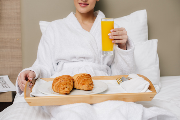 ベッドで朝食をホテルの部屋でバスローブのリラックスで女性のショットをトリミング - 写真・画像