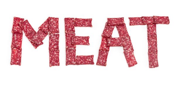 Word MEAT laid out with sausage slices on white background - Photo, Image