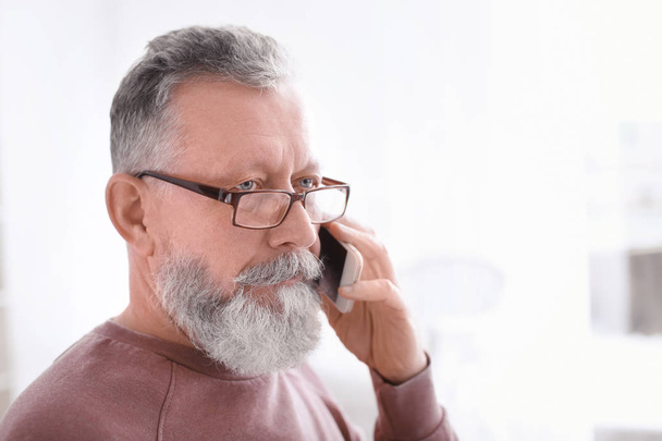 Uomo anziano che parla al cellulare sul posto di lavoro in ufficio
 - Foto, immagini
