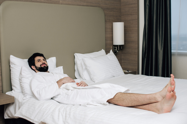 bel homme en peignoir relaxant sur le lit dans la suite de l'hôtel
 - Photo, image
