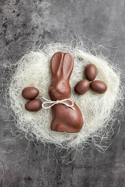 Chocolate Easter bunny and eggs in a nest on rustic background - Foto, Imagen