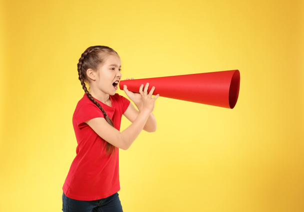Little girl shouting into paper megaphone on color background - 写真・画像