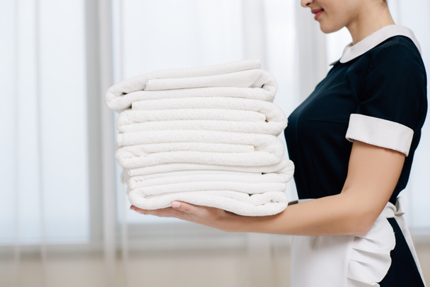 ritagliato colpo di cameriera in uniforme tenuta pila di asciugamani puliti
 - Foto, immagini
