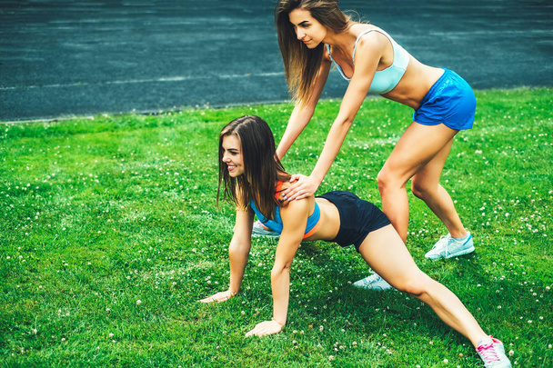Two pretty sporty girls working out together in summer park - Foto, immagini