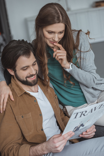 attractive couple reading travel newspaper and planning trip at home - Photo, Image