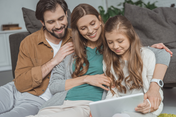gelukkige ouders en dochter met laptop in de woonkamer - Foto, afbeelding