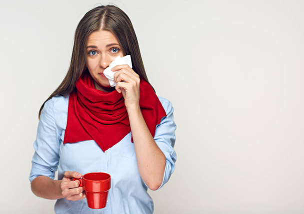  sick woman in blue shirt and red scarf holding coffee cup and handkerchief  - Foto, afbeelding