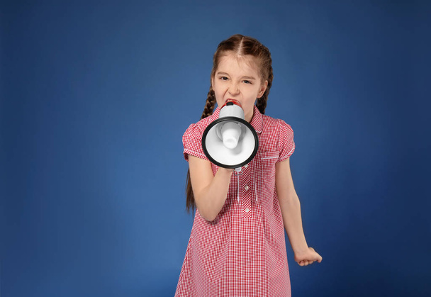 Emotional little girl shouting into megaphone on color background - Photo, image