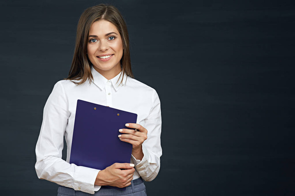 smiling businesswoman holding clipboard with pen on dark background - Foto, immagini
