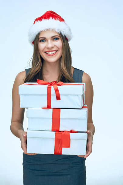 portrait of smiling young businesswoman wearing christmas hat holding paper gift boxes - Fotoğraf, Görsel