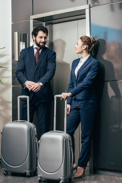 happy young business people with luggage waiting for elevator together - Φωτογραφία, εικόνα