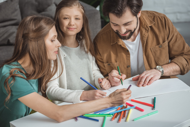 parents and daughter drawing with felt-tip pens at table - Фото, зображення