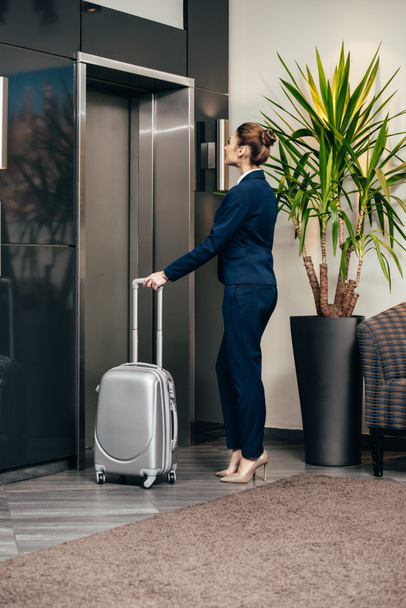 young attractive businesswoman waiting for elevator at hotel with luggage - Foto, Imagem