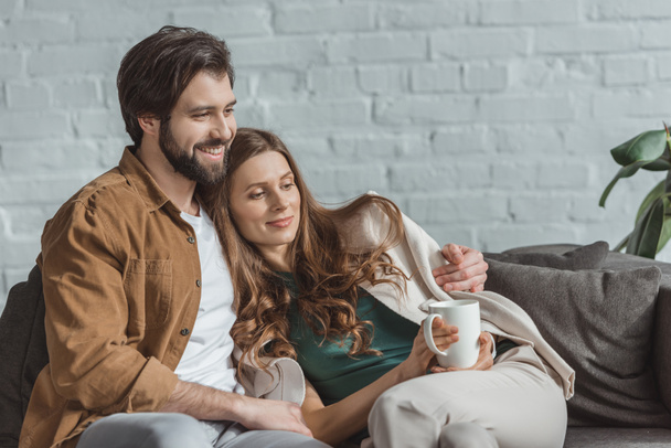 boyfriend hugging girlfriend with cup of coffee at home - Foto, Bild