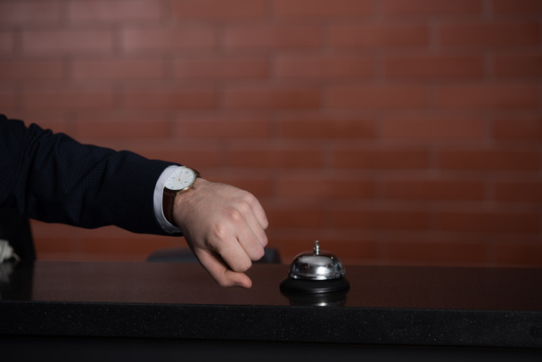 tiro cortado de homem de negócios olhando para o relógio enquanto espera pelo serviço na recepção do hotel
 - Foto, Imagem