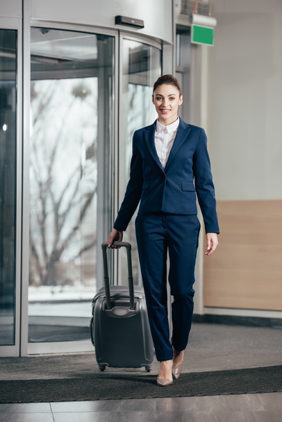 young attractive businesswoman going out of hotel with luggage - Foto, immagini