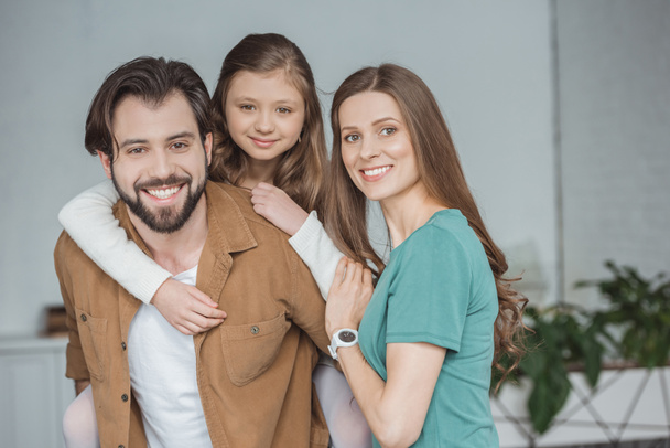 happy parents and daughter looking at camera at home  - Foto, Imagen