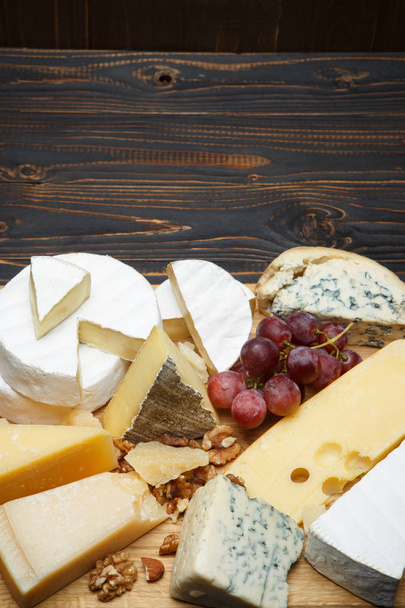 Various types of cheese - parmesan, brie, roquefort, cheddar - Foto, afbeelding