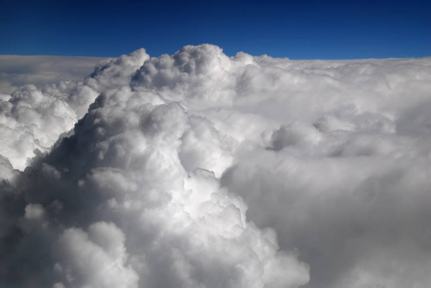 Вид из окна самолета над облаками с голубым небом и облачным пейзажем в солнечное утро. белое кружевное и цирростратное облака. Кучевые облака
 - Фото, изображение